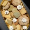 coupelle dorée sur fond noir avec biscuits ronds et carrés et petites meringues